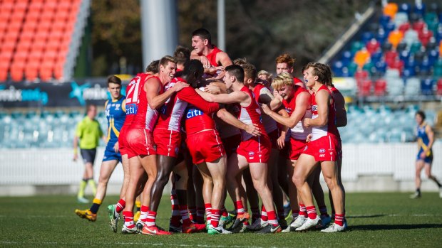 Canberra Demons vs Sydney Swans July 1. Alex Johnson being swarmed by his team mates in celebration after scoring a goal. Photo: Dion Georgopoulos
