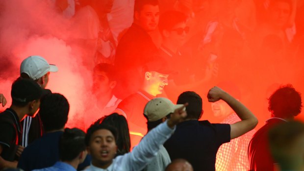A supporter removes a flare after it was ignited in the Melbourne Victory active support area.