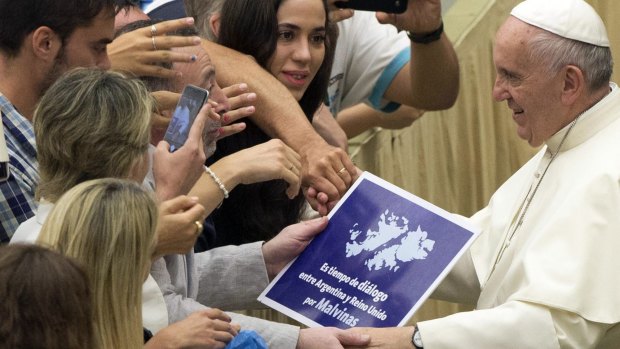A placard which reads, "It's time for dialogue between Argentina and the United Kingdom for Falklands", is held by faithful as Pope Francis is greeted during the weekly audience at the Vatican on Wednesday.