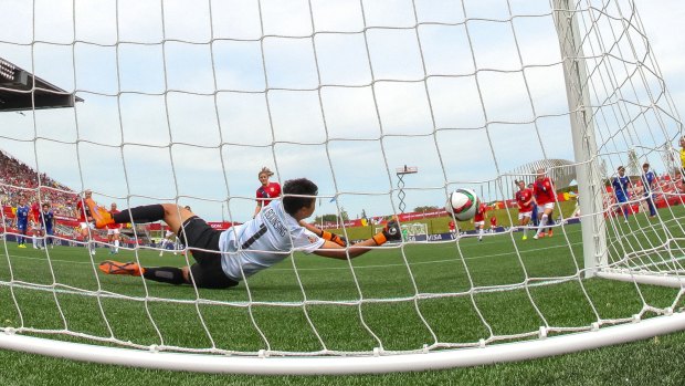 Goalkeeper Waraporn Boonsing dives to save a penalty kick attempt by Maren Mjelde.