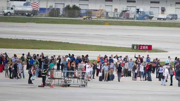 People stand on the tarmac at Fort Lauderdale-Hollywood International Airport after a gunman opened fire. 