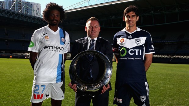 Melbourne City's Kew Jaliens, A-League chief Damien De Bohun, and Melbourne Victory's Guilherme Finkler pose with the A-League championship trophy during a media conference on Monday.