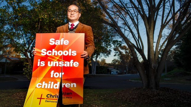 Reverend David Kim with one of the ACT Christian Democratic Party's anti-Safe Schools signs after it had been vandalised.