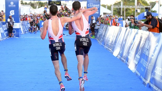Britain's Alistair Brownlee, right, helps his brother Jonny to get to the finish line.