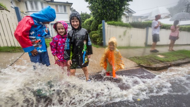 A family plays in the rain brought by ex-cyclone Debbie to Newmarket.
