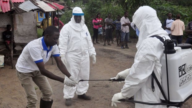 Liberian health workers wash their hands on Tuesday after taking a blood specimen from a child to test for Ebola.