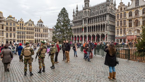 Belgian soldiers patrol as tourists visit the Grand Place in Brussels.