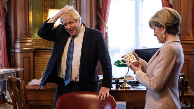 British Foreign Secretary Boris Johnson rubs his head as his Australian counterpart Foreign Minister Julie Bishop inspects his mug which reads 'Foreign Secretary'. 