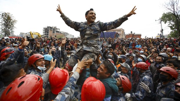 Members of the Nepalese Armed Police Force carry their officer and cheer after successfully rescuing the young survivor.