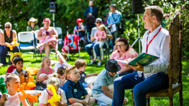On the lawns of the Prime Minister's Lodge in Canberra, Rhys Muldoon reads to children at an event run by a charity serving Canberrans, Hands Across Canberra.