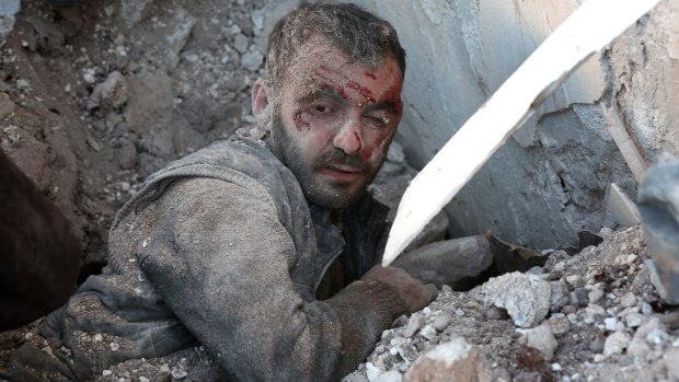A wounded man is trapped under the wreckage of collapsed buildings after air strikes on residential areas in Yaqid al-Adas, near Aleppo.
