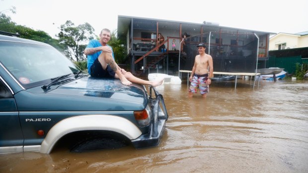 Bennett Wood sits on his car after floodwaters entered his backyard in Murwillumbah.