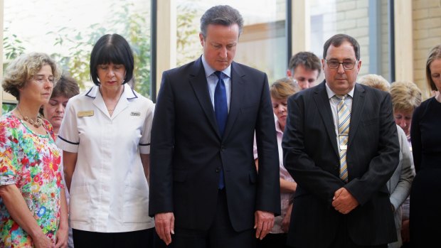 Britain's Prime Minister, David Cameron, centre, stands in silence during a visit to Chipping Norton Health Centre in his constituency in Witney, England.