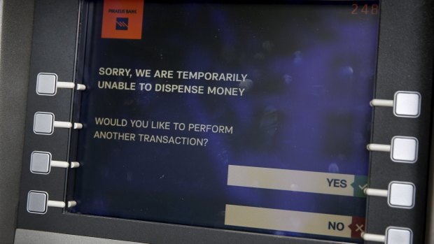 A message is displayed on the monitor of a Piraeus Bank ATM in Athens.
