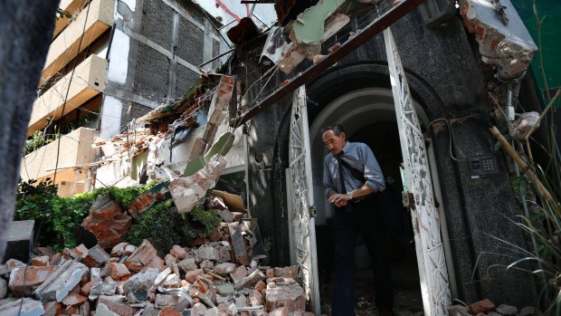 A man walks out of the door frame of a building that collapsed after the earthquake.