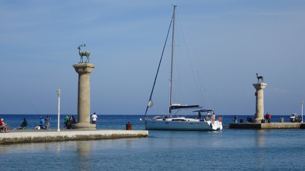 A yacht passes through the old harbour entrance where the Colossus of Rhodes once stood.
