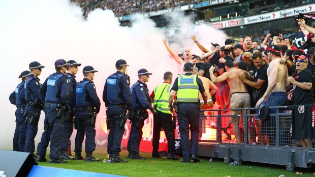 Smoke alarm: Wanderers fans in the crowd let off flares as police officers look on in Melbourne last weekend.