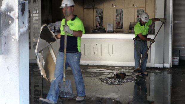 Workers clean up the CFMEU head office in Lidcombe after a car was driven into the foyer and set alight in May 2010.