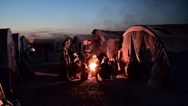 Syrian Kurdish refugees gather around fire in a refugee camp in Suru.