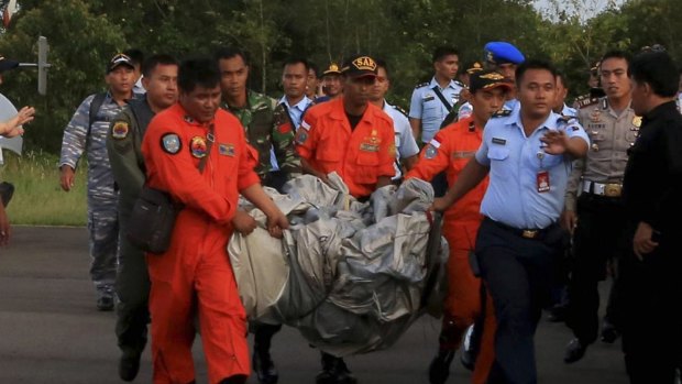 Rescue workers carry debris recovered from the ocean, presumed to be part of the AirAsia plane.