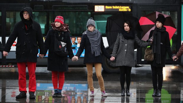 People hold hands and form a circle around the Place de la Republique (Republic Square) at midday in solidarity with victims of the <i>Charlie Hebdo</i> terrorist attack.