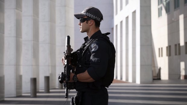 An AFP officer armed with an SR-16 stands guard to the front of Parliament House in Canberra in October. 