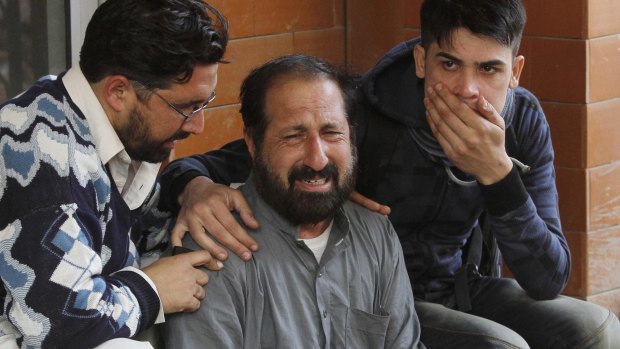 Relatives of a student, who was injured during an attack by Taliban gunmen on the Army Public School, comfort each other outside Lady Reading Hospital in Peshawar.