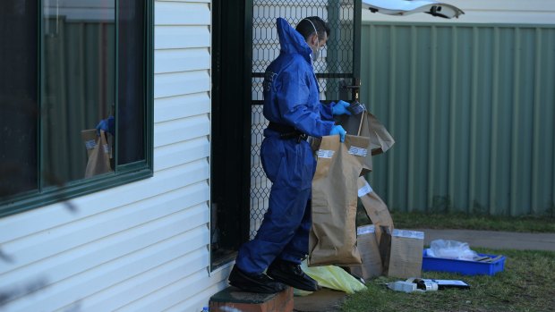 A NSW Forensic officer carries evidence bags into the backyard of Vincent Stanford's home.