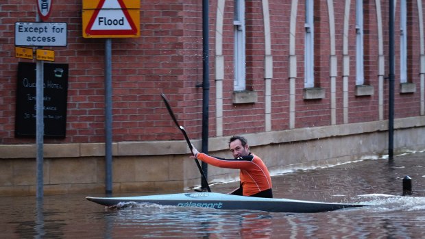 A man paddles his kayak along a flooded street  in York on Sunday.