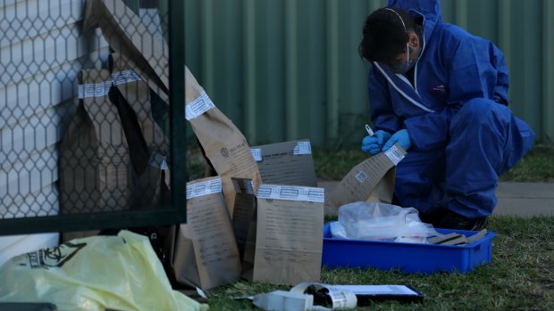 A NSW forensic officer writes on evidence bags in the backyard of Vincent Stanford's home.