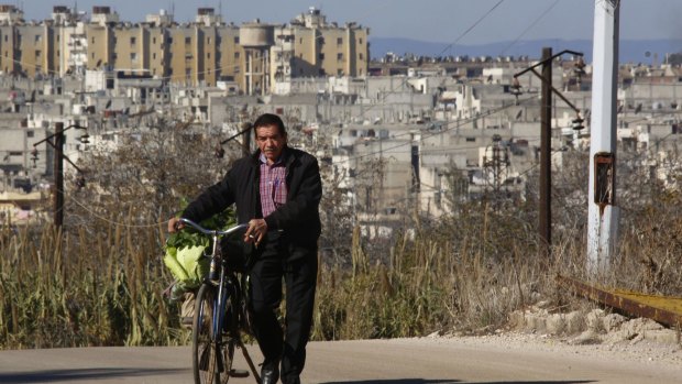A man pushes his bicycle in an area adjacent to the Waer neighbourhood in the central city of Homs.