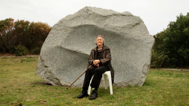 May Barrie sitting in front of her sculpture <i>Time and Tide Granite Monolith II</i>. 
