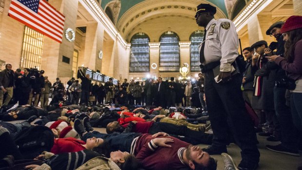 A police officer stands next to activists staging a "die-in" during rush hour at New York's Grand Central Station.