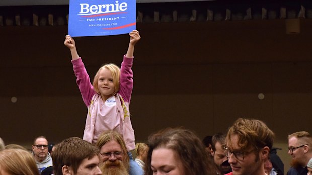 A five-year-old holds up a "Bernie Sanders for President" sign while sitting on her father's shoulders at the Juneau Democratic Caucus in Alaska on Saturday.