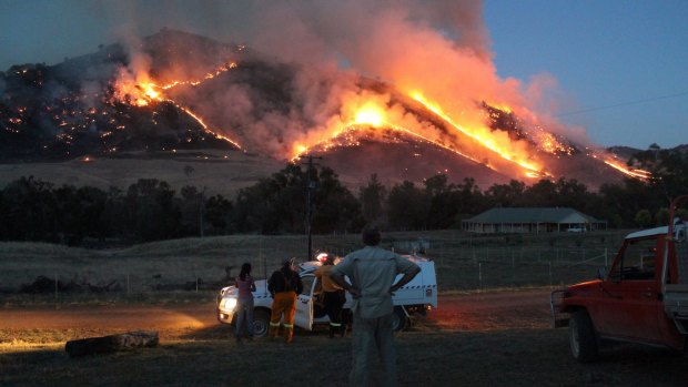 People watch on as a fire burns near Jugiong. A hotter summer this year means an increased risk of fires in the ACT.
