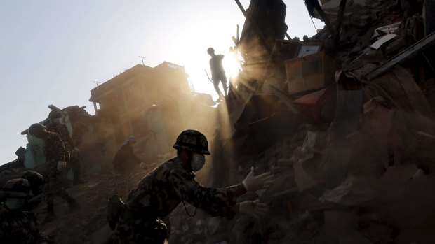 Nepal army personnel and earthquake survivors search for belongings at a collapsed house on the outskirts of Kathmandu.    