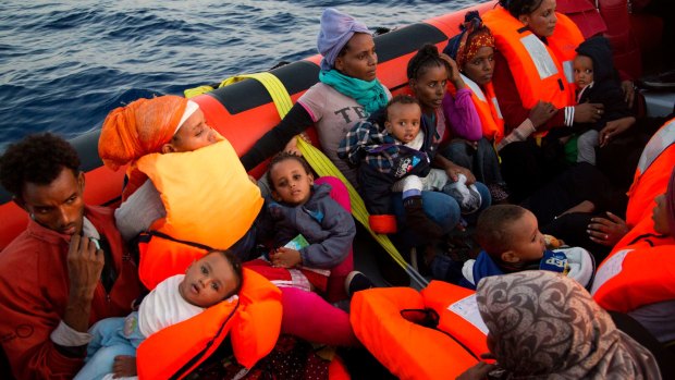 Migrants from Eritrea hold their children after being rescued from a crowded wooden boat fleeing Libya.