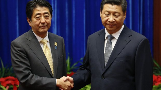 Uncomfortable: China's President Xi Jinping (right) shakes hands with Japan's Prime Minister Shinzo Abe.