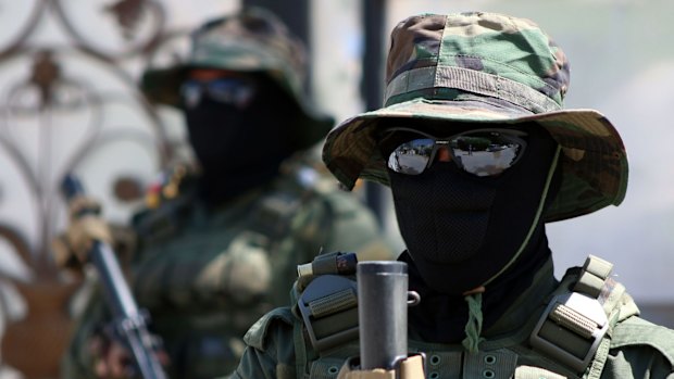 Iraqi fighters of the Shiite militia Asaib Ahl al-Haq stand guard outside their headquarters.