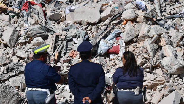 Police officers view the remains of a building in Amatrice following the deadly quake.