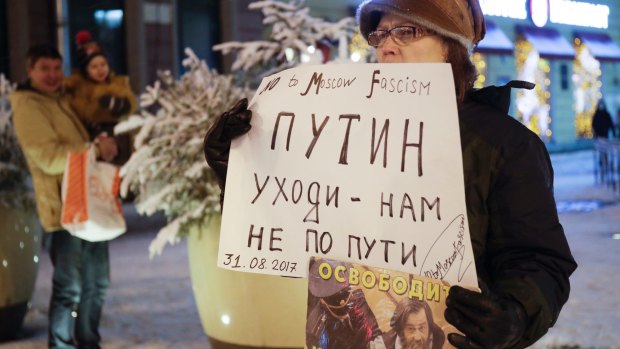 A protester stands in a one-person picket, holding a poster reading 'Putin go away-we do not follow your path!' in St.Petersburg, Russia.