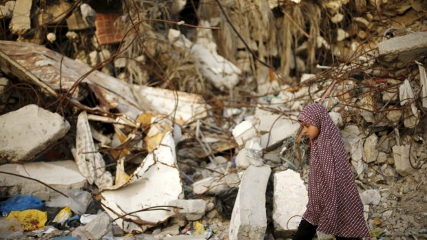 A Palestinian girl walks past a house destroyed during Operation Protective Edge in Gaza City.