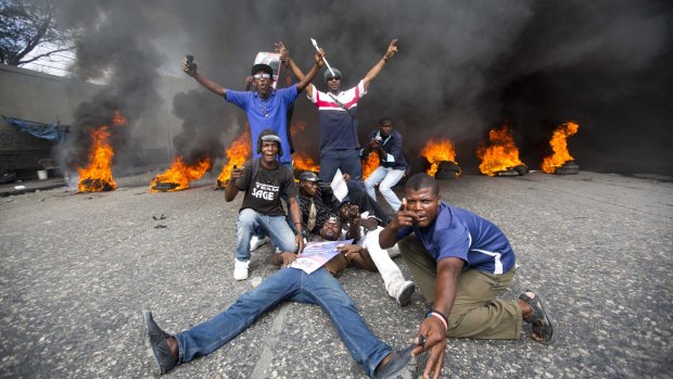 Demonstrators pose in front of a burning barricade during a protest to demand the president's resignation.