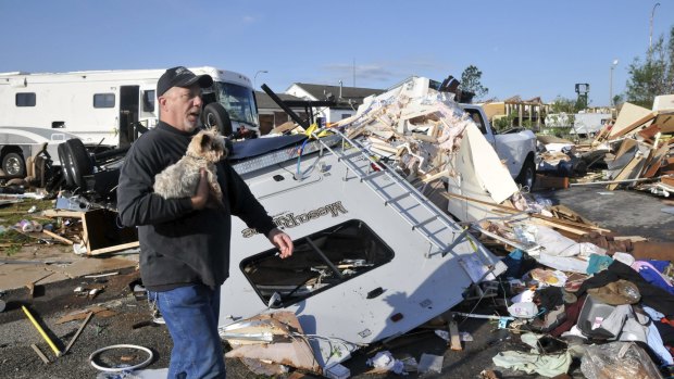 Damon Braley carries his mother's dog Sammy, which he rescued from under the wreckage of his parents' RV, at the Roadrunner RV Park in Oklahoma City.