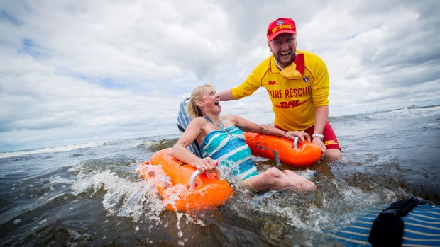 Amanda Lawrie-Jones enjoys a dip in a floating wheelchair with the help of St Kilda life saver Simon Lewis.