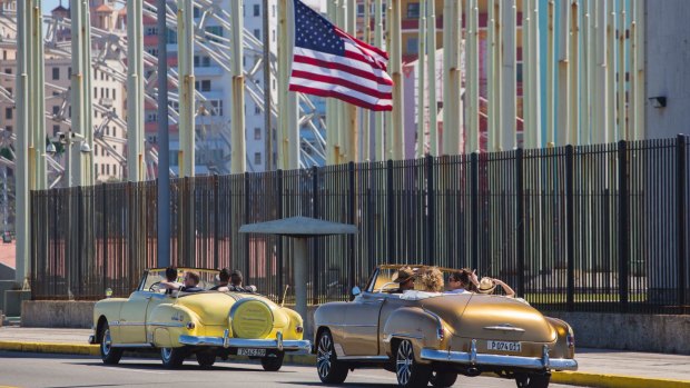 Tourists ride vintage American convertibles as they pass by the United States embassy in Havana, Cuba.