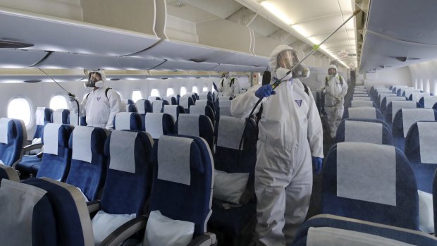 Workers wearing protective gears spray disinfectant inside a plane at Incheon International Airport in South Korea.