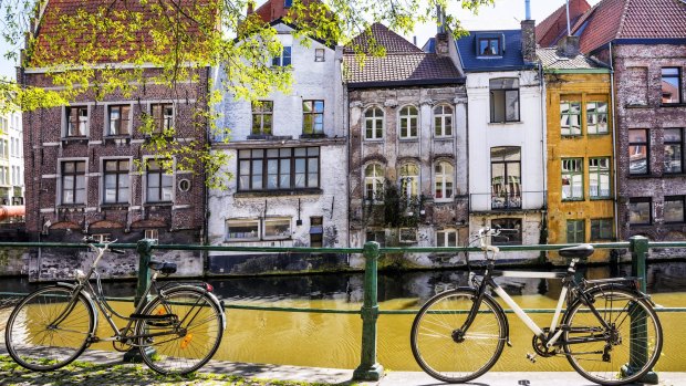 Bicycles parked by the canal in front of the old medieval houses in Ghent.