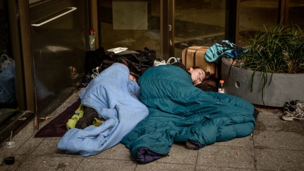 A couple sleep through the mid-morning on the corner of Collins and King Streets.