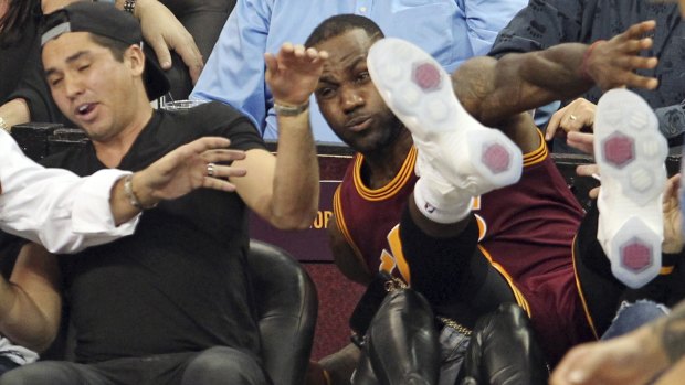 Real risk: Cleveland Cavaliers' LeBron James falls into Ellie Day, as Jason Day takes cover.